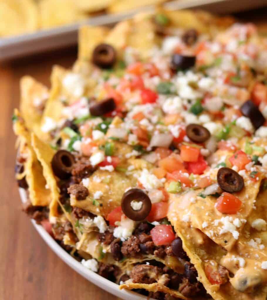 trash can nachos copycat on a plate with olives, pico de gallo, and queso fresco on top