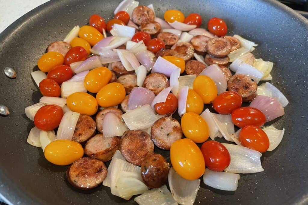 chicken sausage, shallots, and tomatoes in a skillet with olive oil