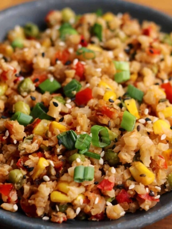 fried cauliflower rice in a bowl with scallions and sesame seeds