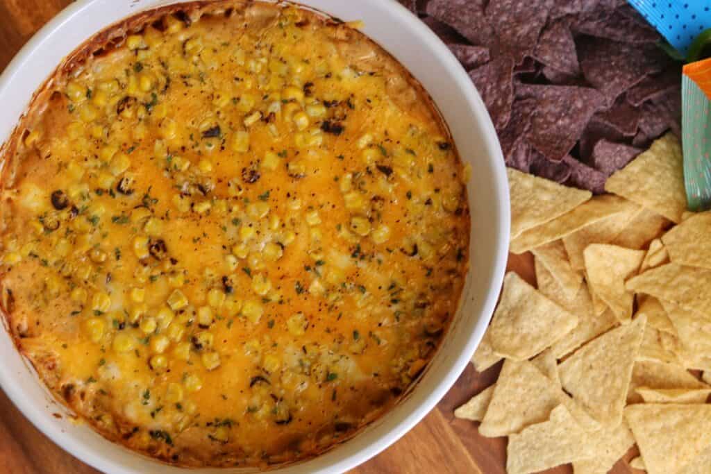 large bowl of chicken dip with two types of tortilla chips beside the bowl