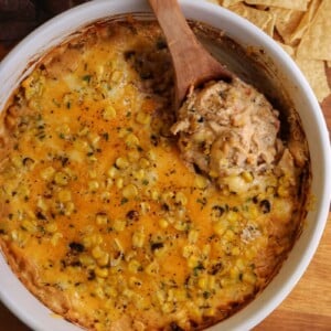 large bowl of chicken dip with two types of tortilla chips beside the bowl
