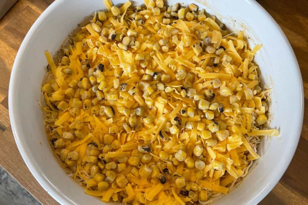 shredded cheddar and trader joe's fire roasted corn on top of the chicken dip before baking
