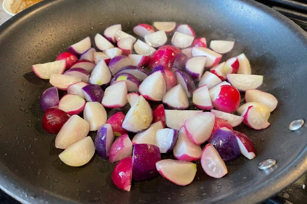 quartered radishes in a skillet with olive oil