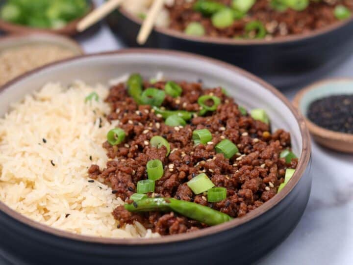 Mongolian ground beef in a bowl with basmati rice, green onion, and toasted sesame seeds