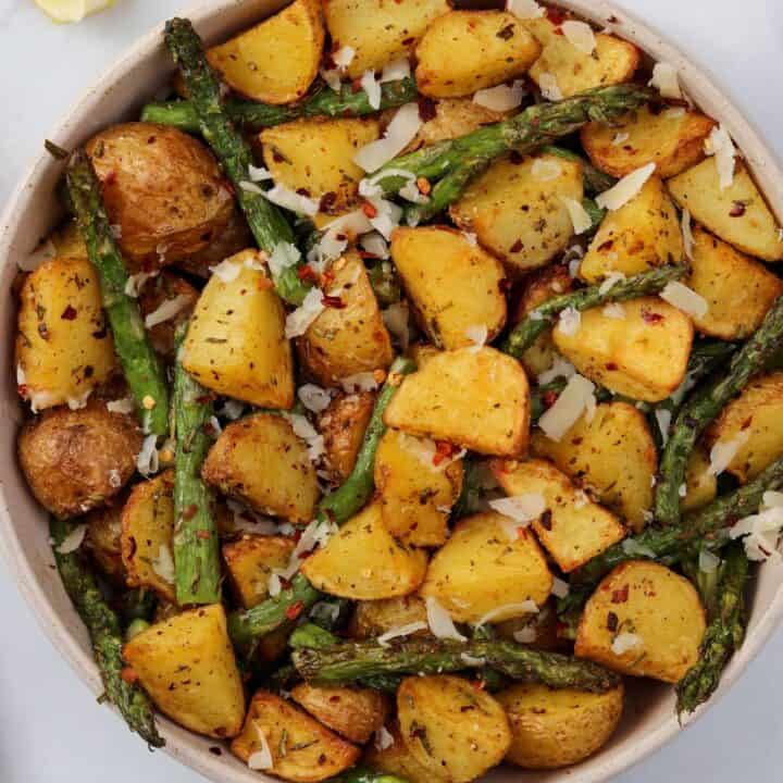 air fryer asparagus and potatoes in a bowl with grated parmesan and lemon