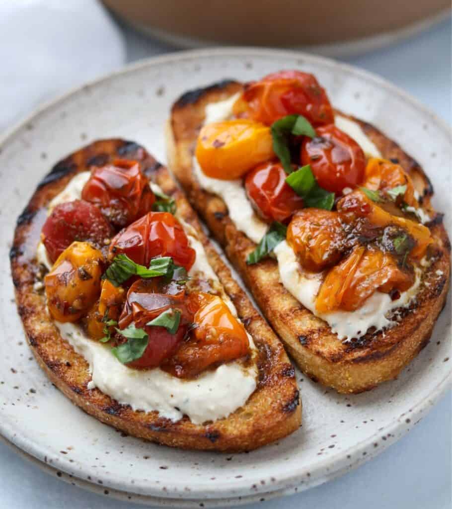 two slices of grilled ciabatta bread topped with the whipped feta dip and roasted tomatoes