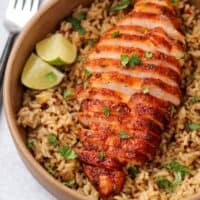 smoked chicken breast sliced on a bed of rice with lime wedges