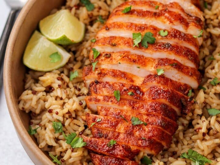 smoked chicken breast sliced on a bed of rice with lime wedges