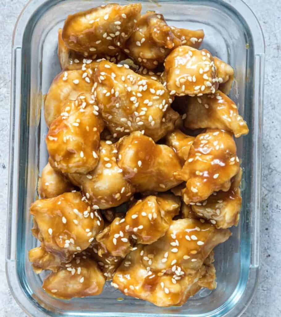 orange chicken in a meal prep container with sesame seeds