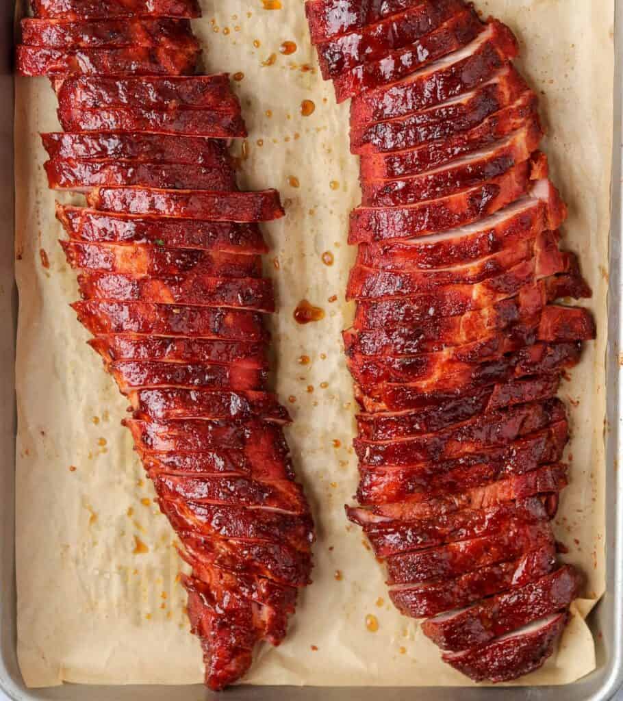 sliced bbq smoked pork tenderloin on a sheet pan lined with parchment paper