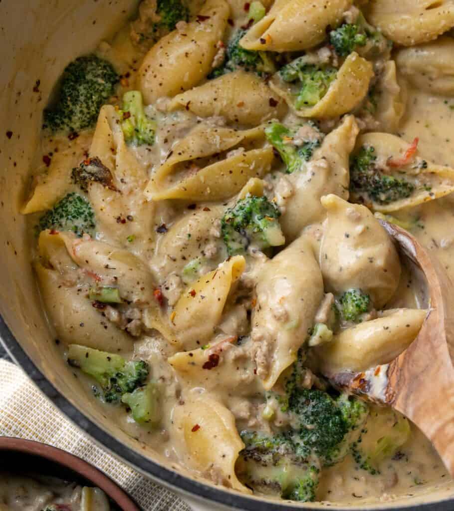 broccoli and turkey pasta in a Dutch oven with a wooden spoon serving