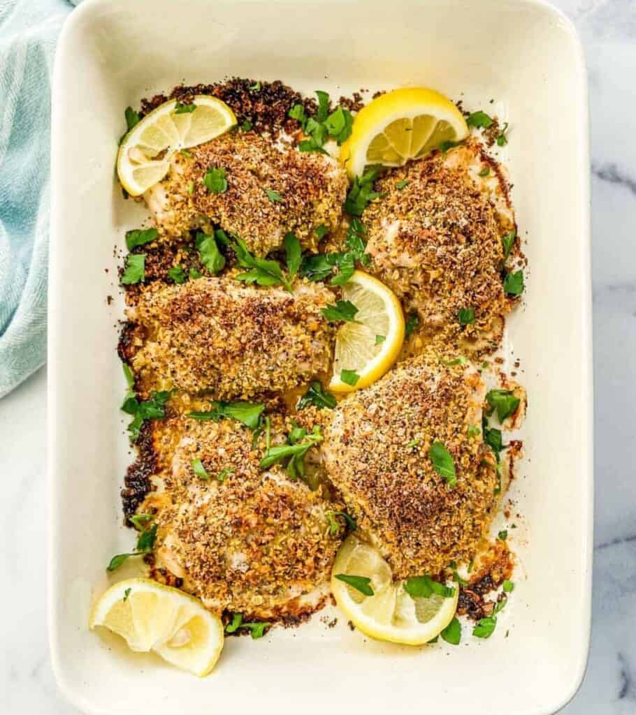 chicken in a baking dish with lemon wedges and parsley