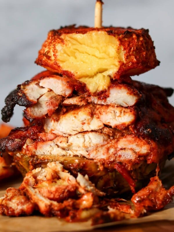slicing roasted chicken al pastor with pineapple on a skewer