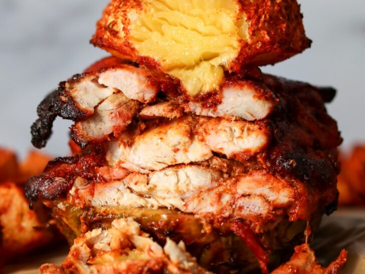 slicing roasted chicken al pastor with pineapple on a skewer
