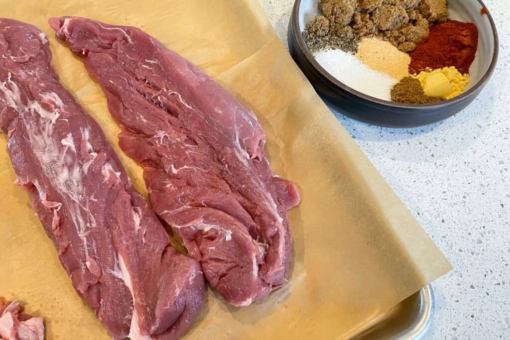 trimmed pork tenderloins beside the bbq rub ingredients in a bowl
