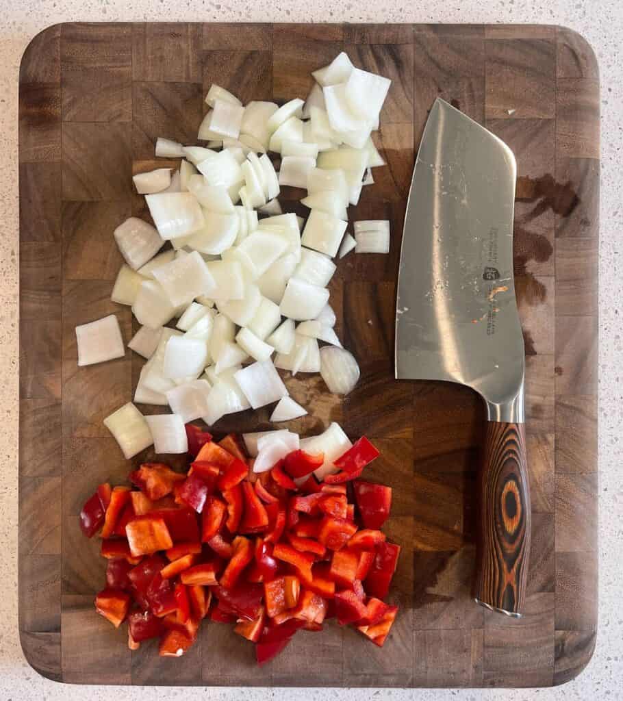 large diced yellow onion and red bell pepper on a cutting board