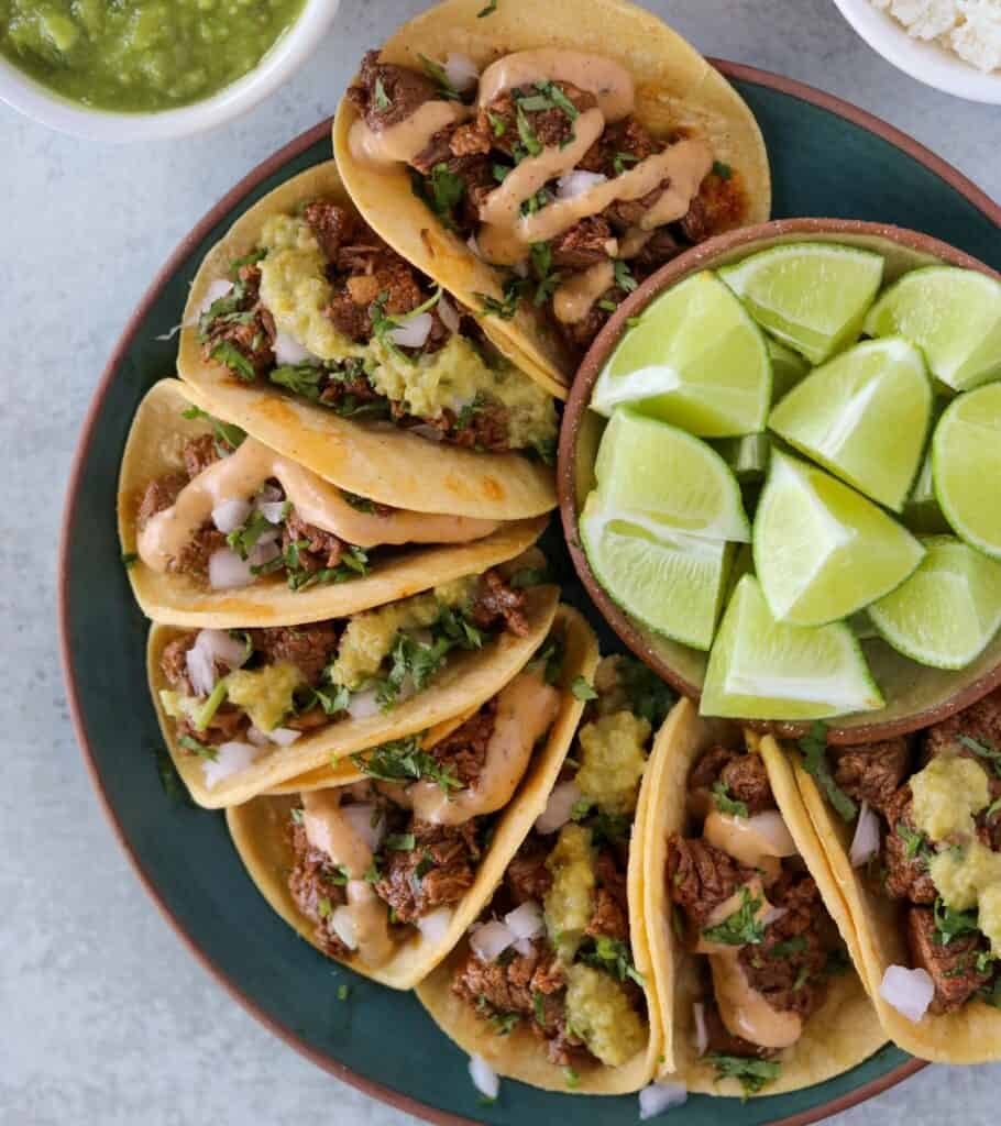 steak street tacos on a plate with a bowl of limes