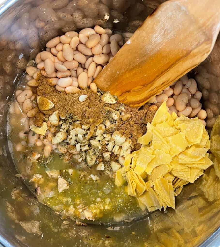 salsa verde, chopped garlic, chopped tortillas, ground cumin and coriander, dried oregano, and white beans in a pot