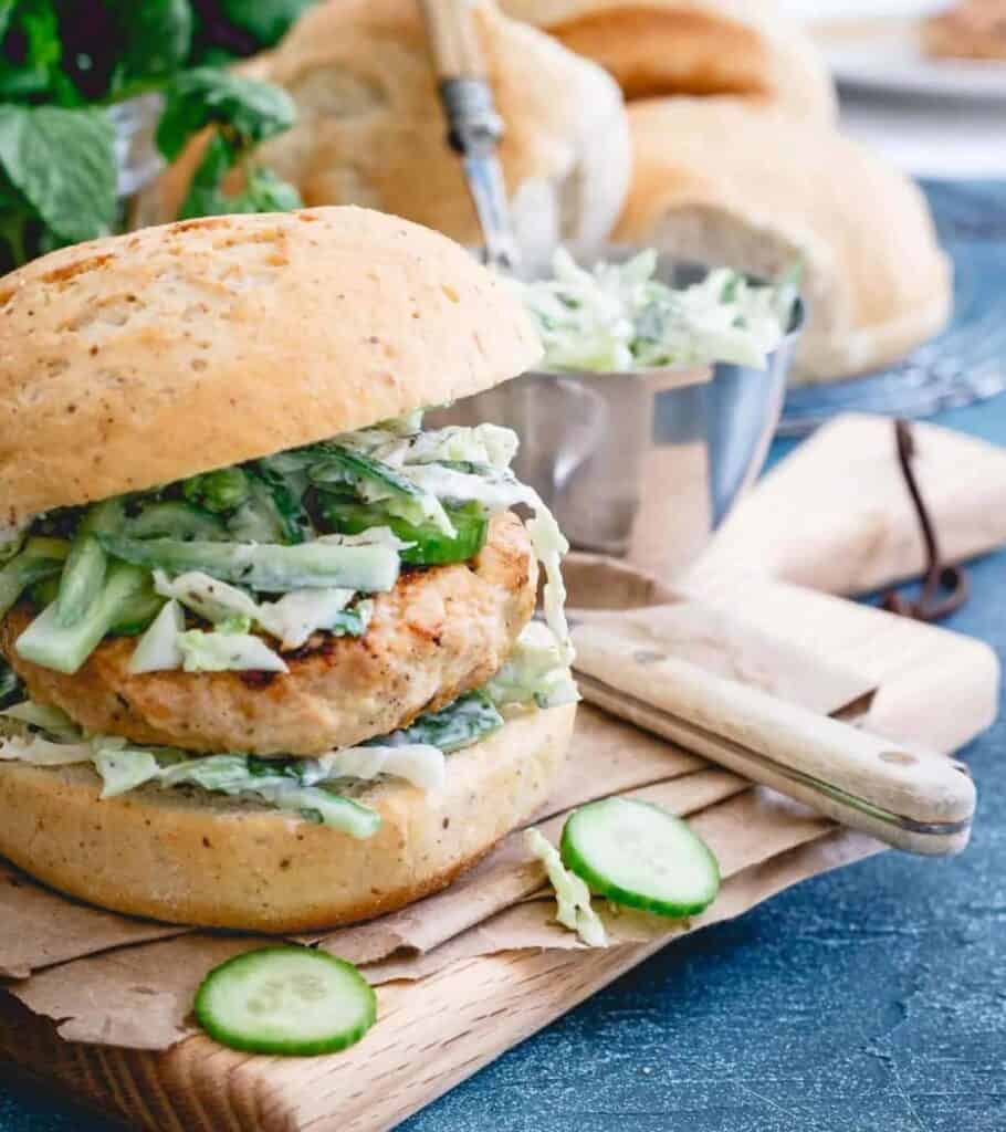 chicken burger on a cutting board with cucumber slaw