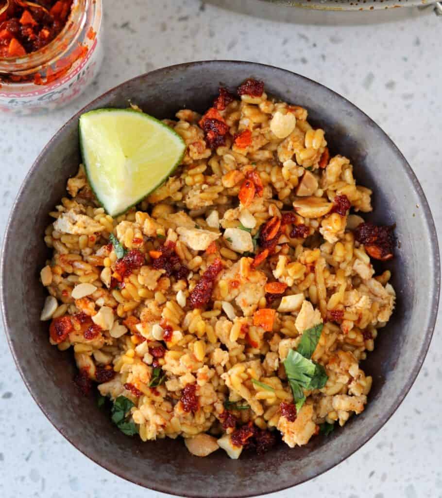 chicken and rice in a bowl with chili crisp and lime