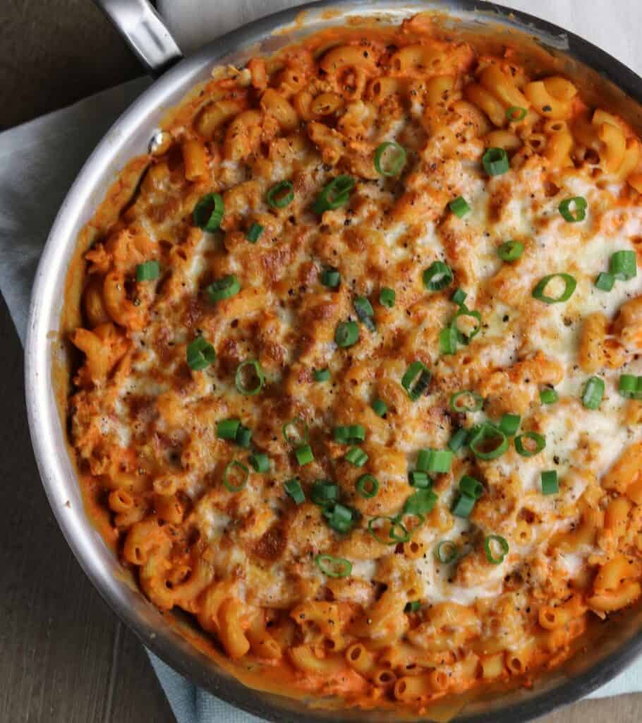 buffalo chicken mac and cheese in a skillet topped with green onion