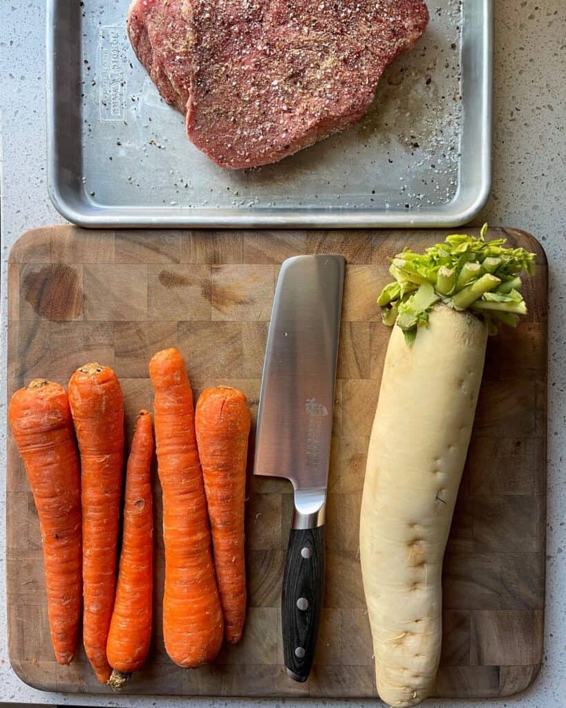 daikon radish and carrots on a cutting board for pot roast