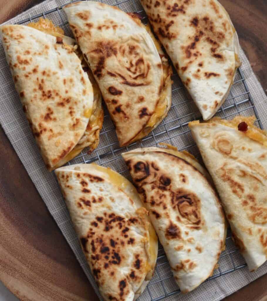 six quesadillas on a wire rack before cutting into triangles