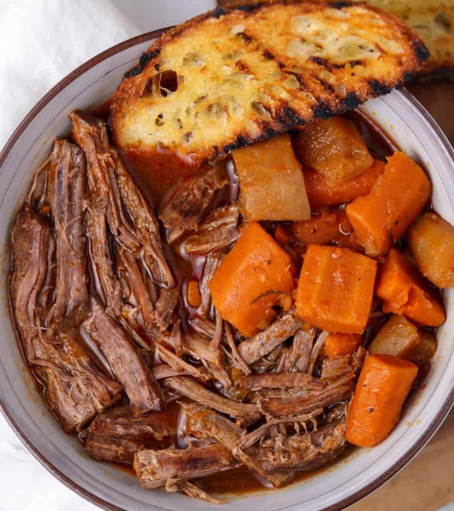 pot roast and carrots in a bowl with grilled bread