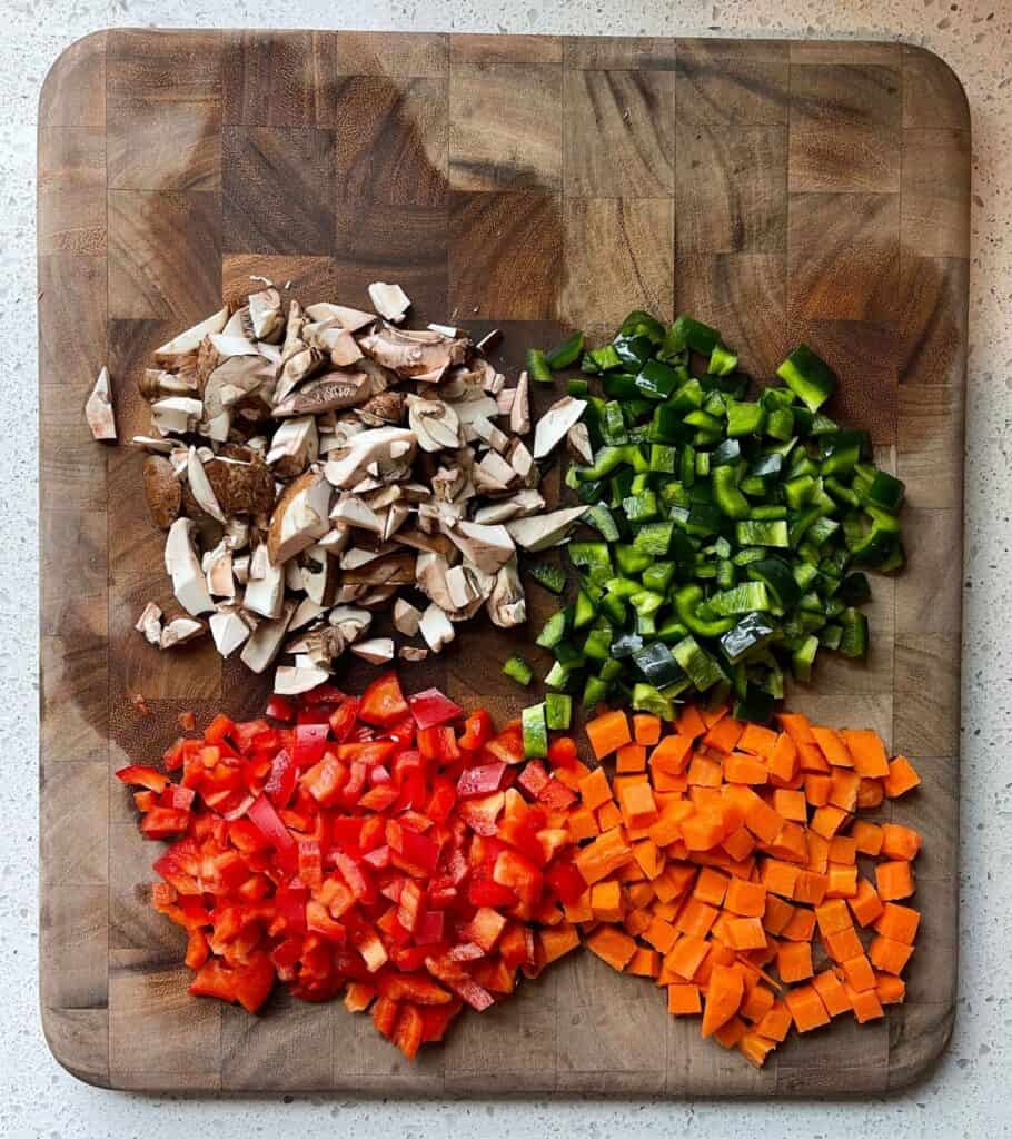 mushrooms, poblano pepper, red bell pepper, and carrots on a cutting board