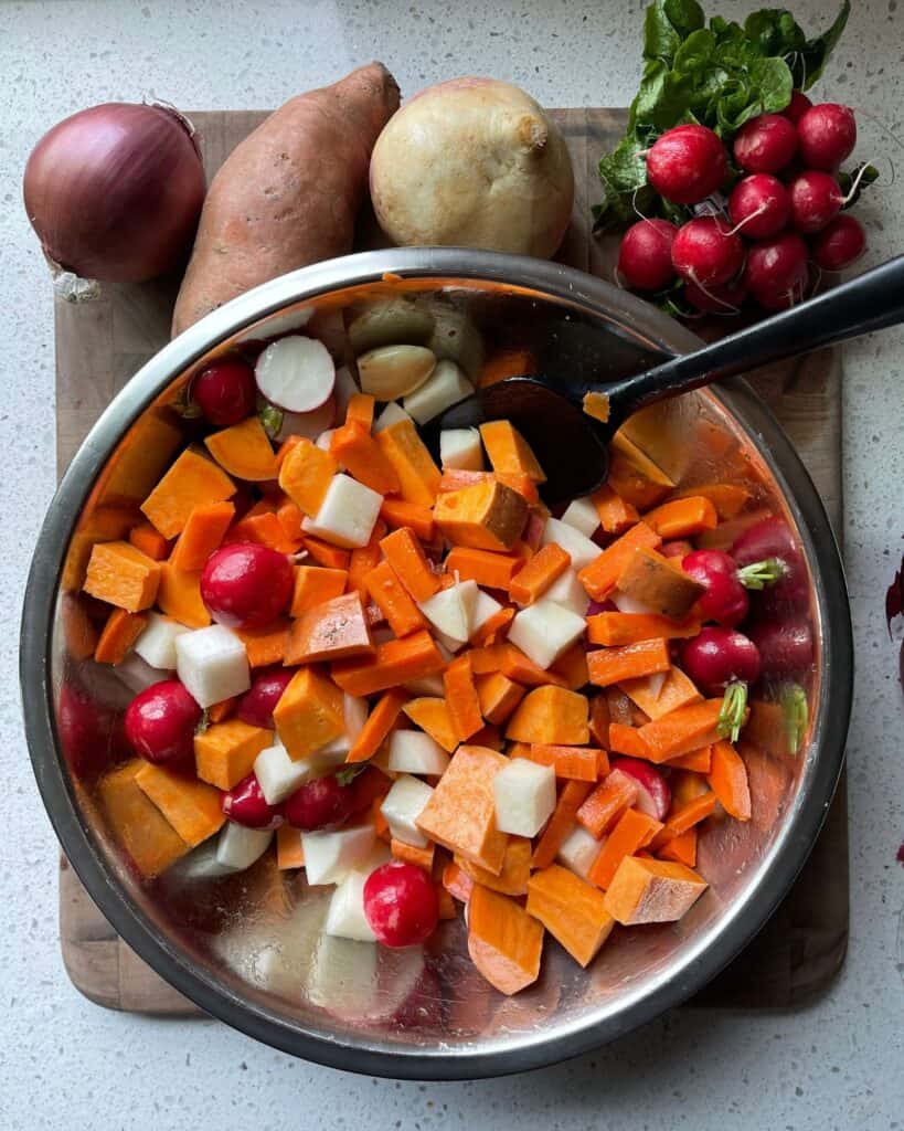 mixing bowl with red radishes, carrots, sweet potatoes, and turnips
