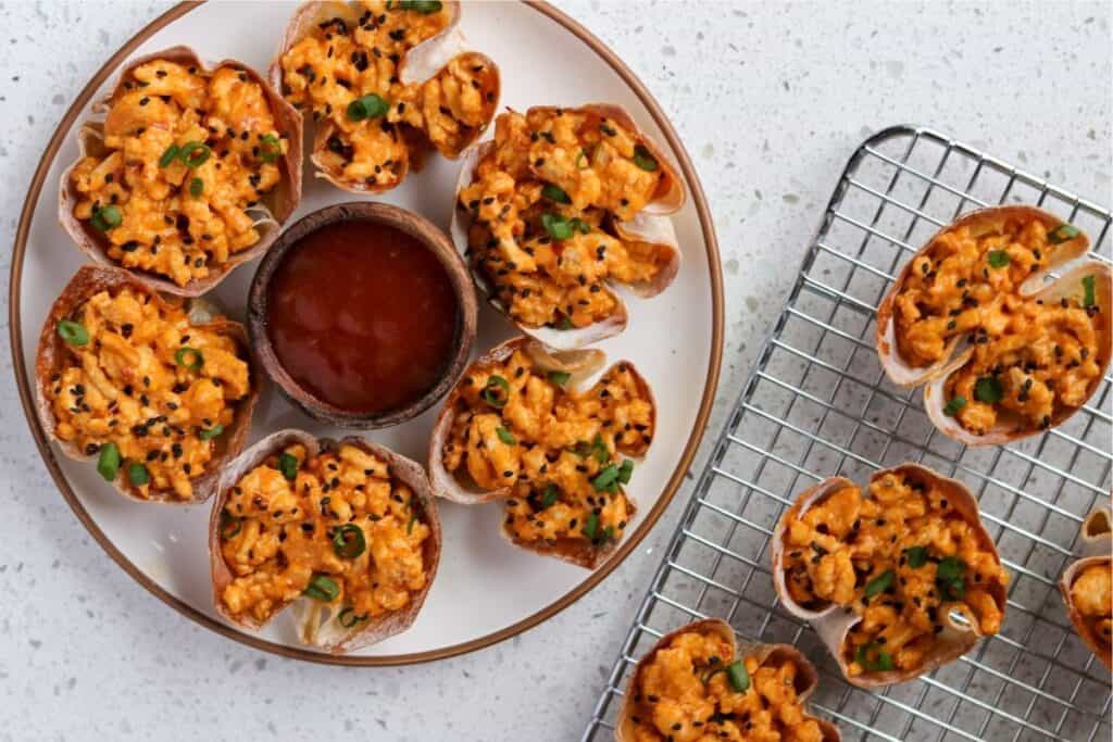 6 bang bang chicken wonton cups on a plate with sweet chili sauce