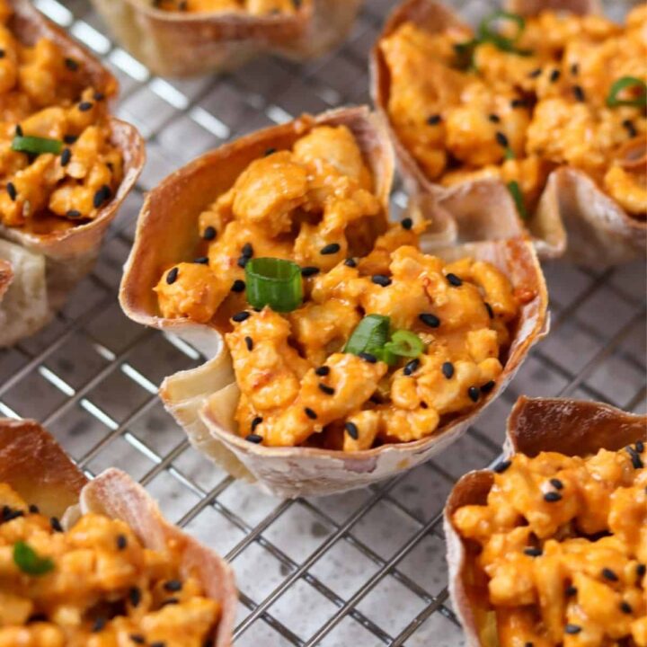 bang bang chicken wonton cups on a wire rack topped with sesame seeds and green onion