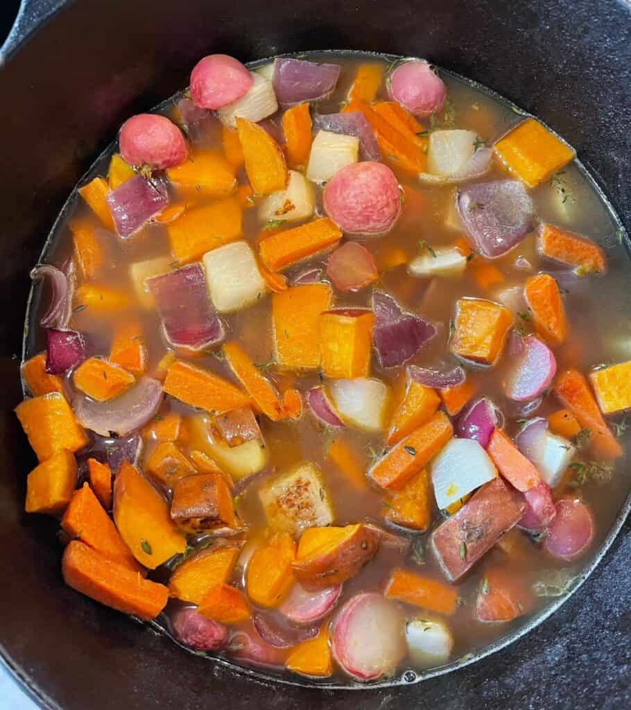roasted root vegetables in a pot with broth