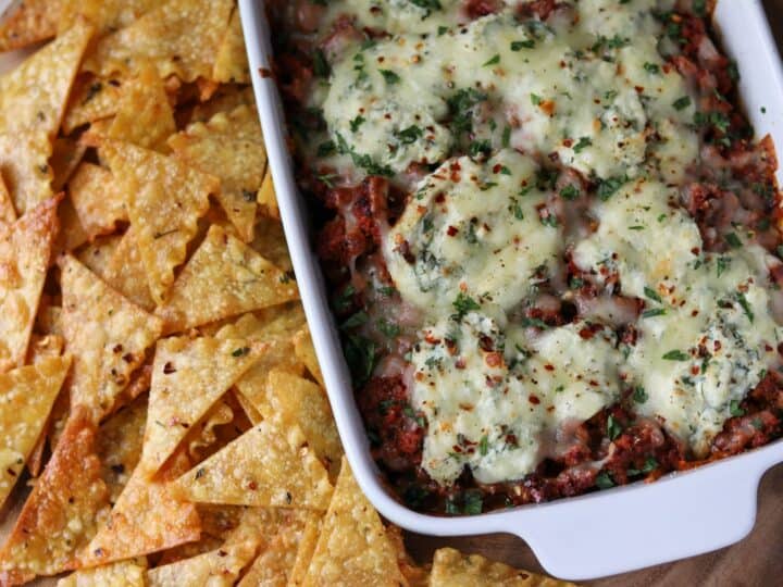 baked pasta chips beside a baking dish filled with lasagna dip
