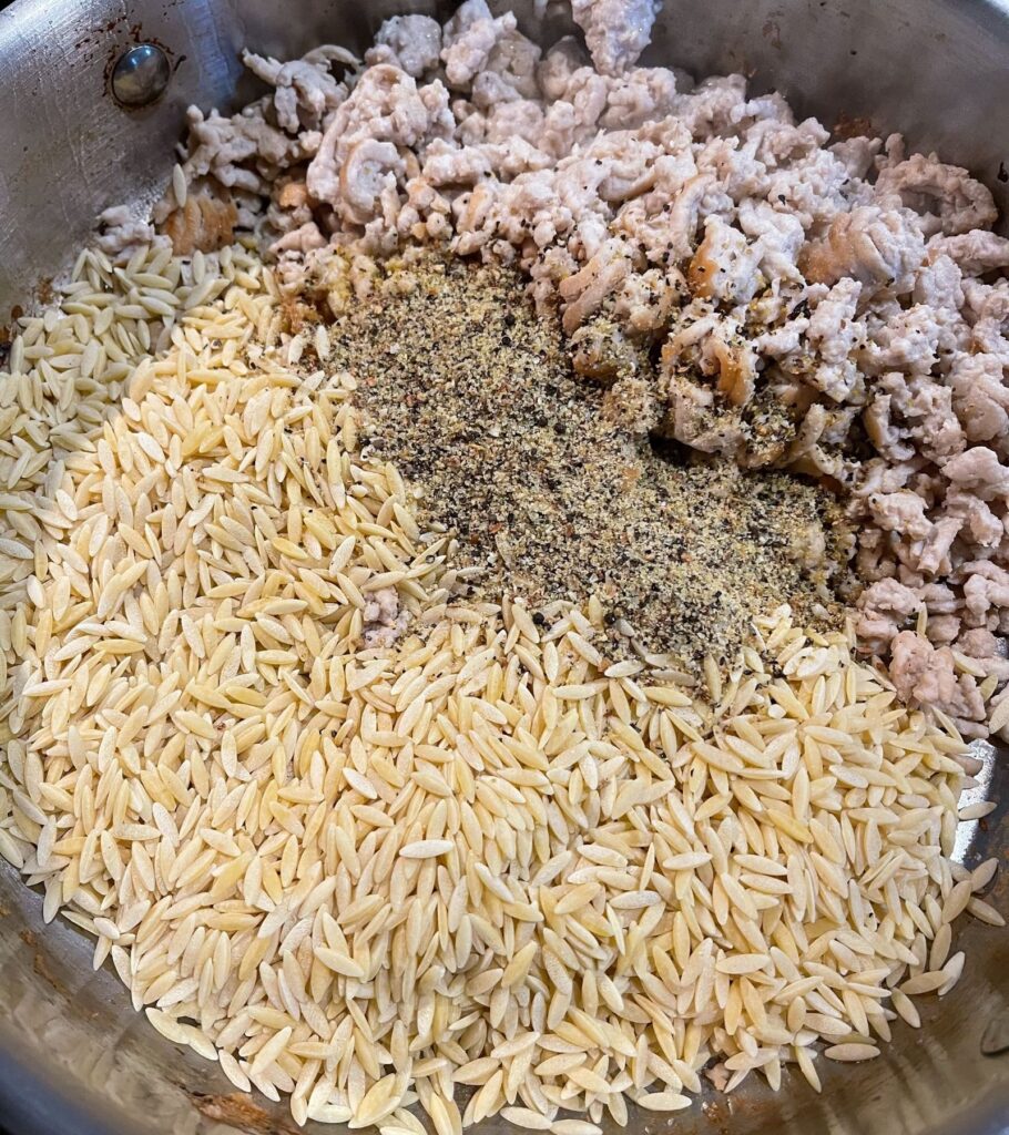 cooked ground turkey in a skillet with orzo and lemon pepper seasoning