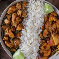 bowl with long grain rice, sweet chili chicken bites, cucumber crunch, and lime wedges