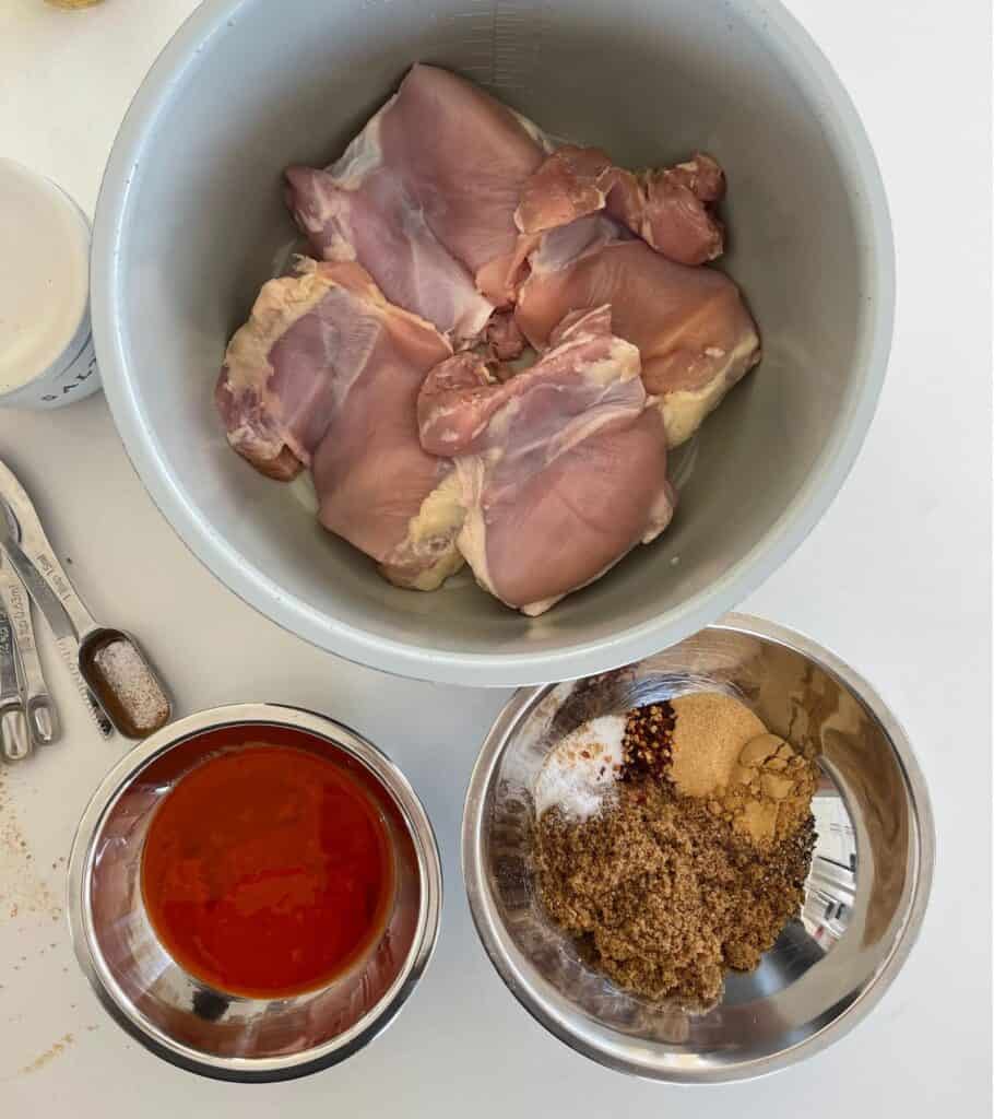 boneless skinless chicken thighs in a Ninja Foodi pot beside a bowl of firecracker sauce ingredients
