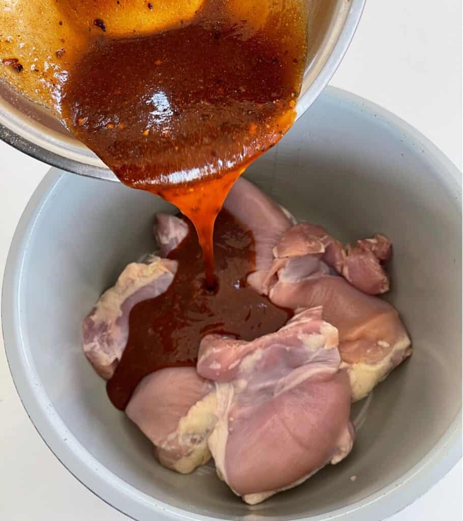 pouring the firecracker sauce over the chicken thighs