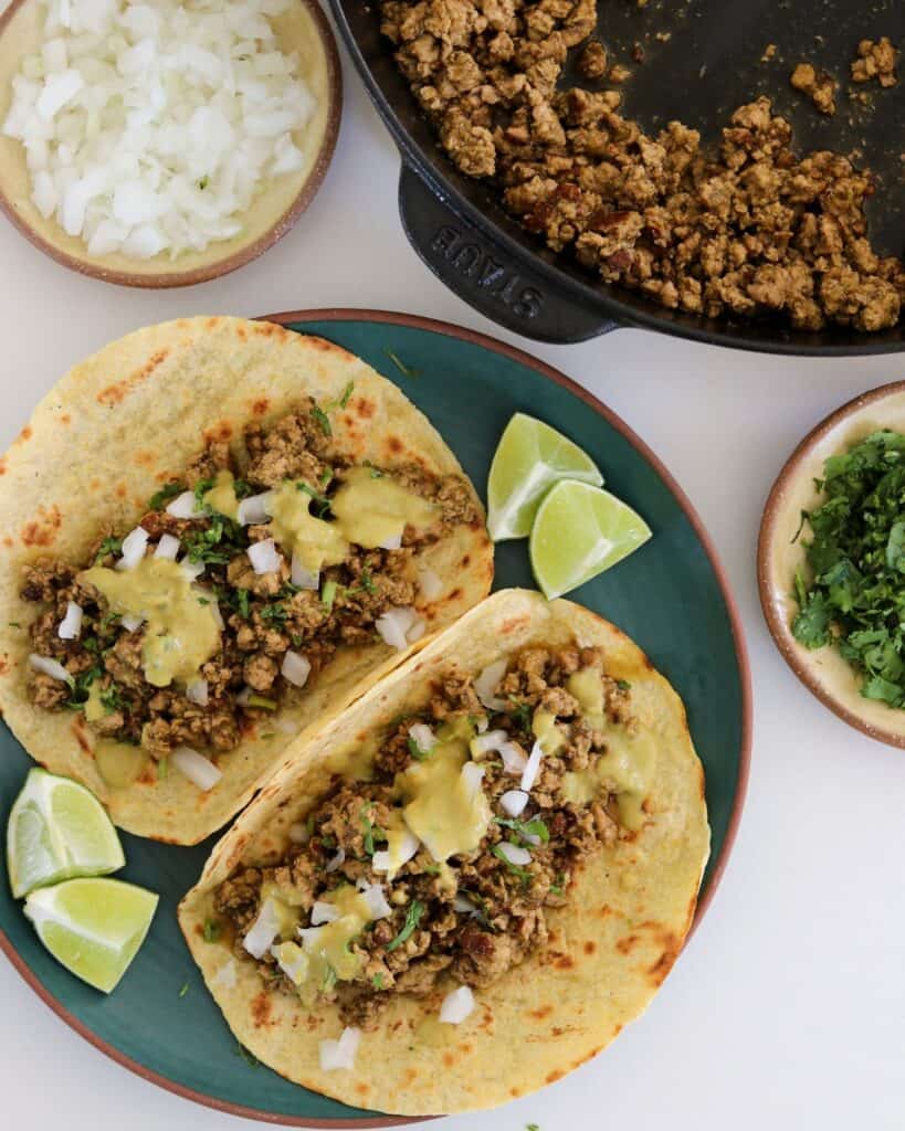 green chile ground pork in a pan beside two ground pork tacos 