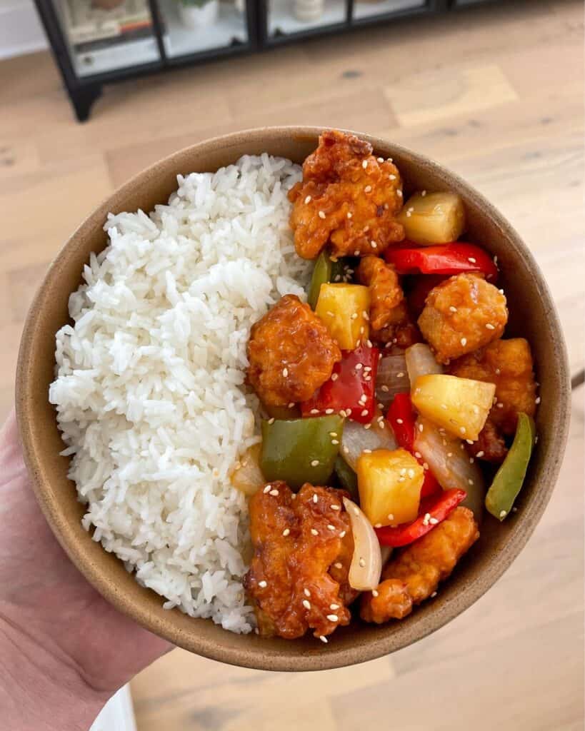 a bowl of rice topped with sweet and sour chicken