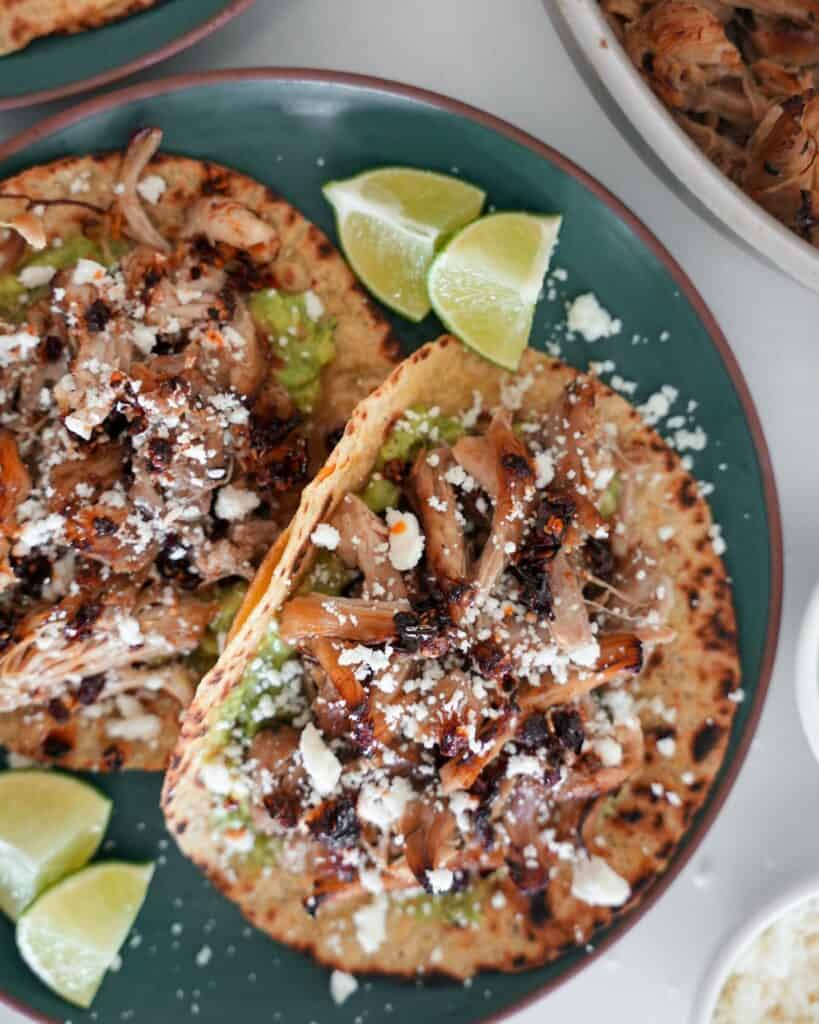 two chicken carnitas tacos with lime wedges