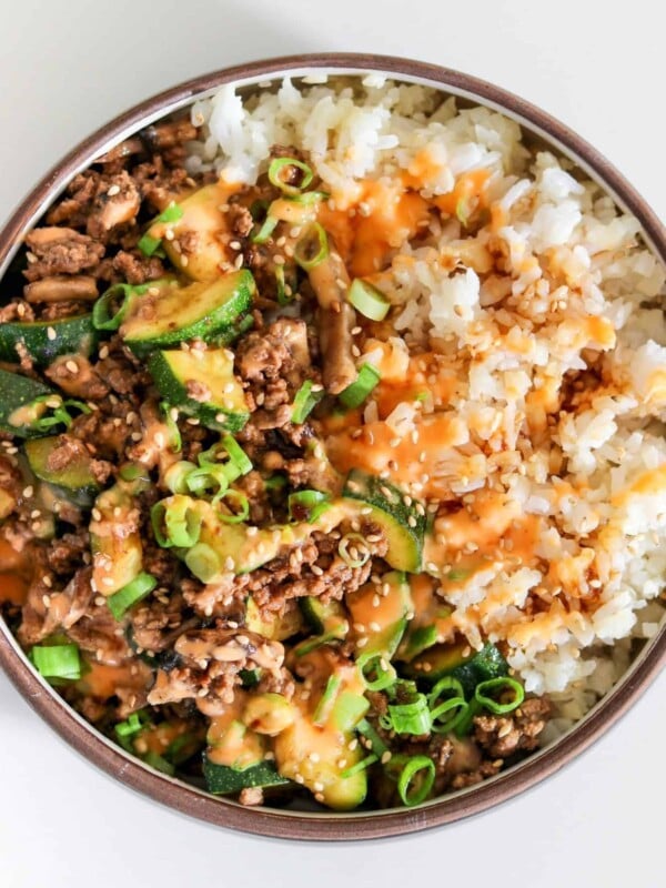 teriyaki ground beef stir fry over rice with yum yum sauce, sesame seeds, and scallions
