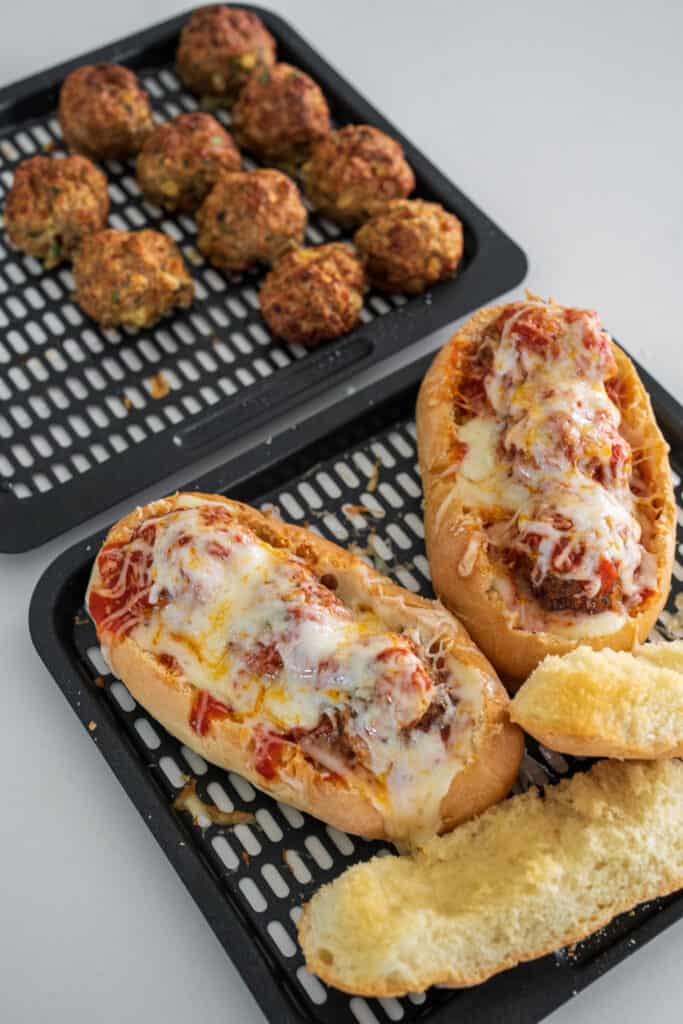 turkey meatball subs on an air fryer basket with extra meatballs