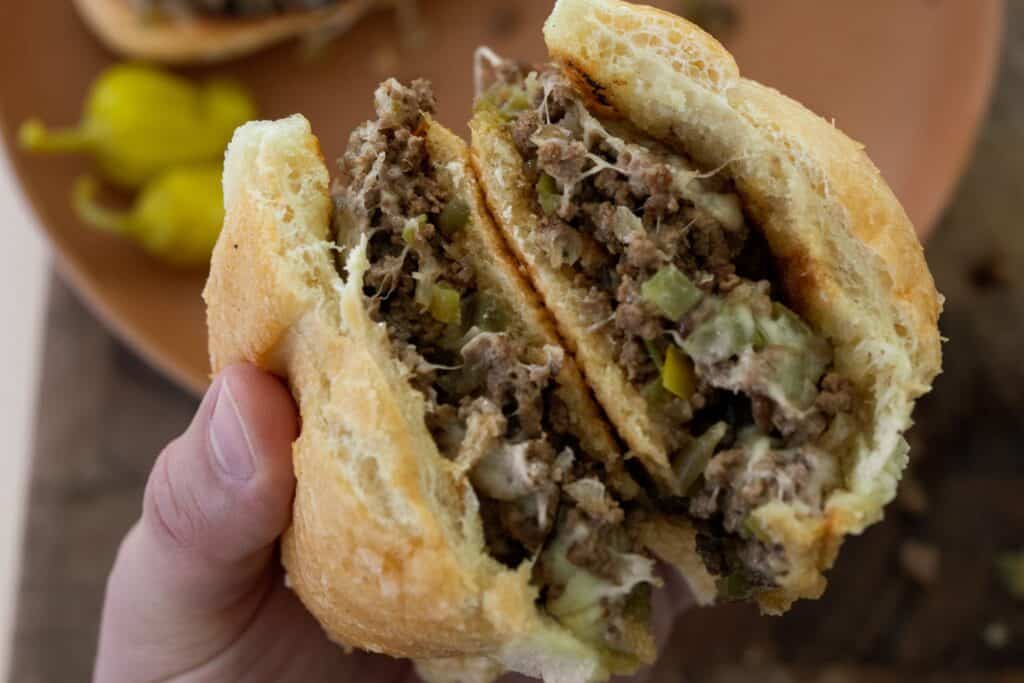 holding a ground beef cheesesteak sandwich