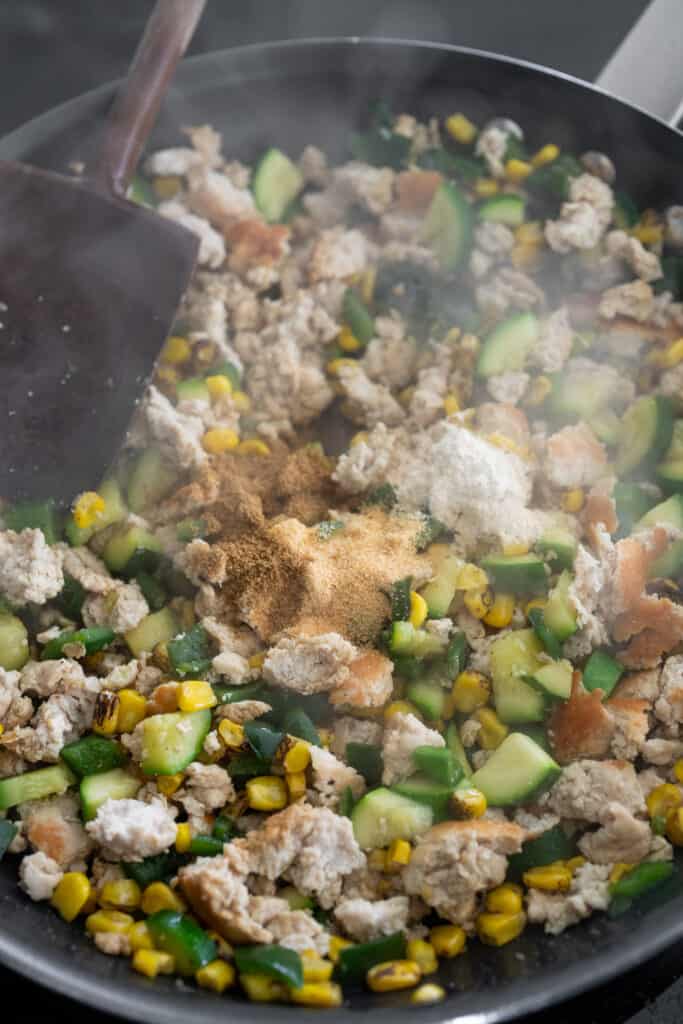 ground turkey and veggies in a skillet with seasoning