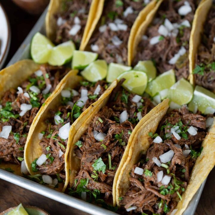 shredded beef tacos with lime, cilantro, and onion