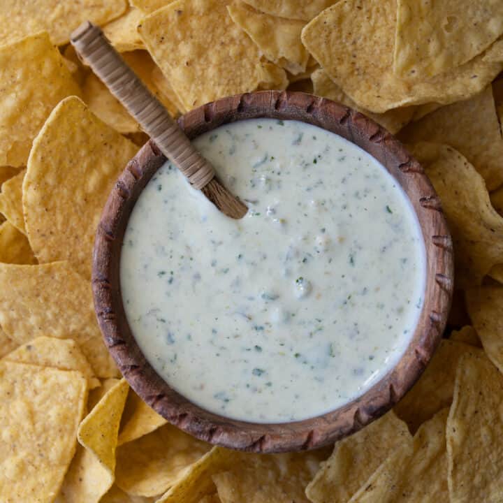 wooden bowl of creamy jalapeño Greek yogurt dip on a tray with tortilla chips