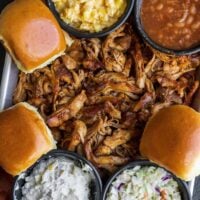 Dutch oven shredded chicken on a tray with sides and rolls