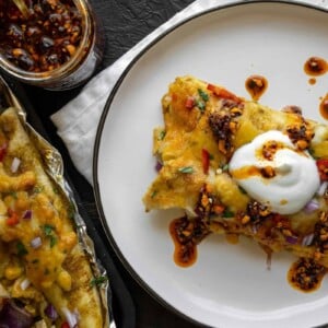 two roasted veggie enchiladas on a plate with Greek yogurt and salsa macha