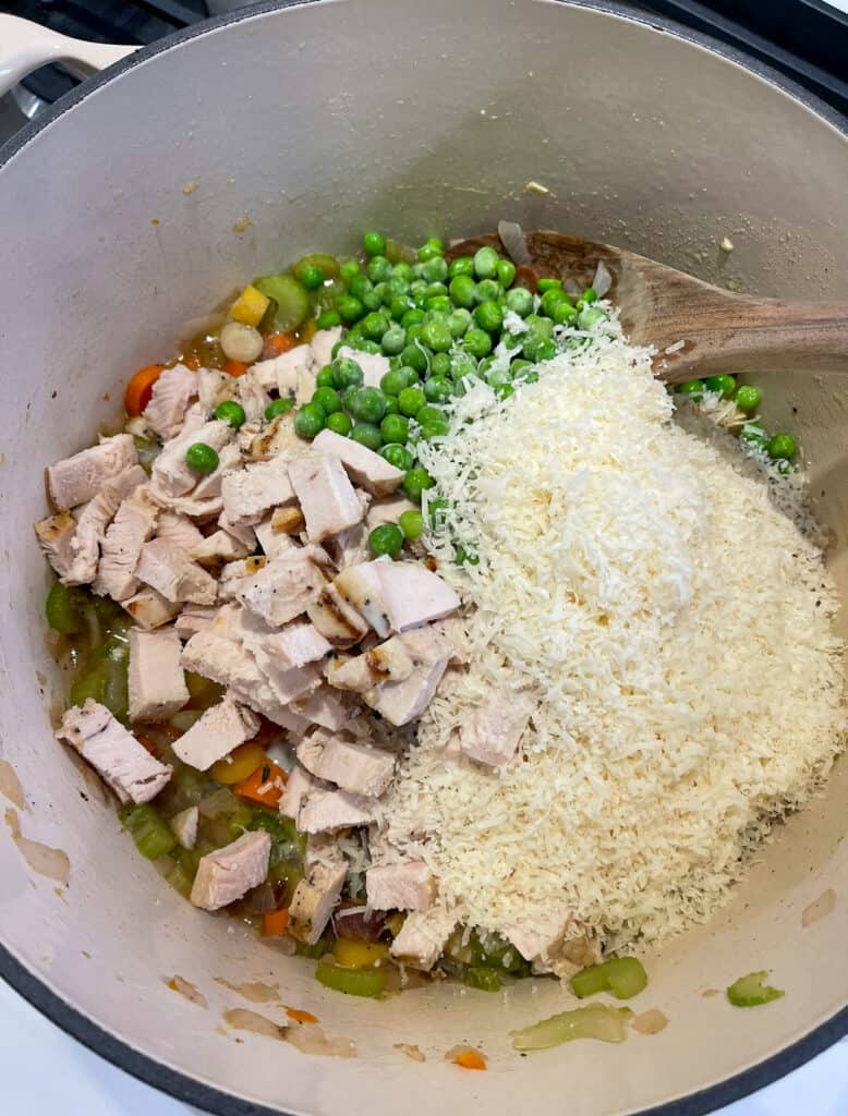 grated parimigiano reggiano, grilled chicken, and frozen peas in a Dutch oven